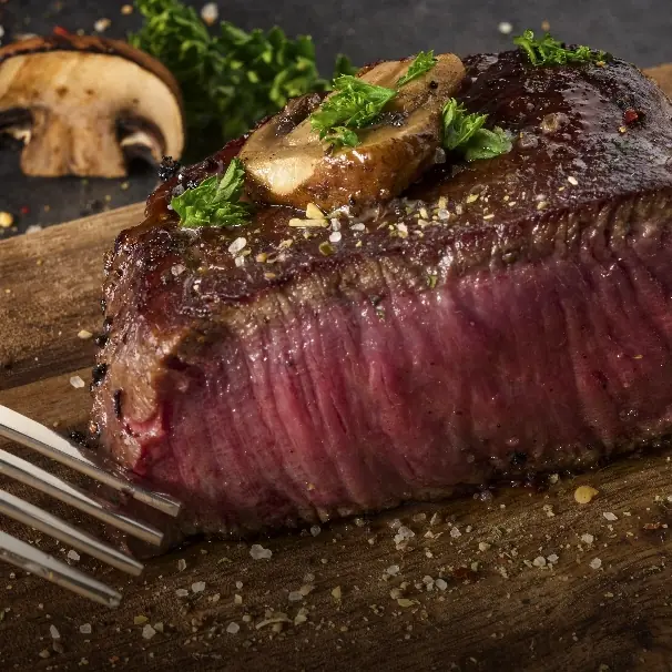 A thick cooked steak topped with herbs and mushrooms